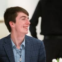 Young man laughs while sitting at table